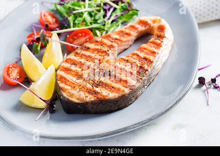 Salmone. Bistecca di pesce al salmone alla griglia e insalata di pomodori con microgreens. Cibo sano. Foto Stock