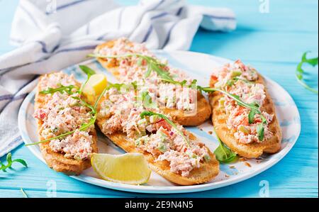 Bruschetta con salmone al forno. Tapas. Sandwich con salsa di salmone, feta, avocado, pomodori e cipolla rossa. Toast con salmone al rione. Foto Stock