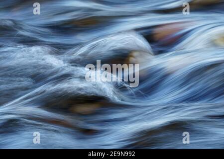 Primo piano di rapide d'acqua sfocate dal movimento che scorrono su una pietra di Cobble Letto sul fiume Foto Stock