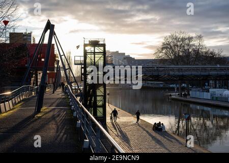 La gente si diverte alla fine della giornata nel Parc de la Villette lungo il Canal de l'Ourcq. Foto Stock