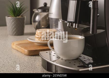 Moderna macchina per caffè espresso con una tazza all'interno della cucina. Foto Stock
