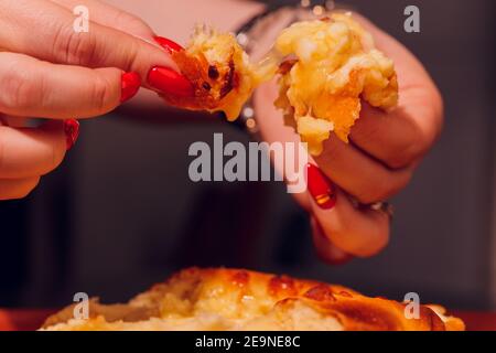 La donna sta mangiando il khachapuri adjariano con le mani, schiacciando il tuorlo d'uovo Foto Stock