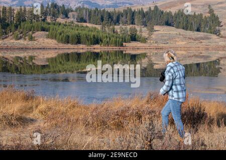 Nord America, Wyoming, Parco Nazionale di Yellowstone. Riflessioni del mattino presto sul lago Swan con una fotografa femminile. Solo per uso editoriale. Foto Stock