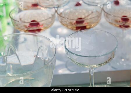 Cubetti di ghiaccio secco in un primo piano in una tazza di vetro vicino alla piramide di champagne. Ghiaccio secco per effetto fumo quando il cameriere inserisce il ghiaccio nel bicchiere di vino frizzante. Foto Stock