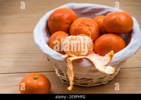 Tangerini (arance, clementine, agrumi) in un cesto di vimini su sfondo di legno con spazio per la copia Foto Stock