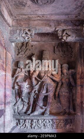 Badami, Karnataka, India - 7 novembre 2013: Templi in grotta sopra il lago Agasthya. Statua rossastra di Arkhanarishvara, Shiva e Parvati combo. Nandi e Bhri Foto Stock