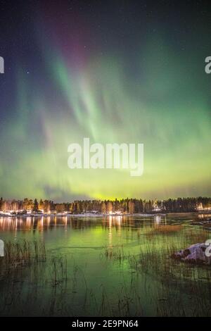 Aurora boreale su lago ghiacciato e innevato Foto Stock