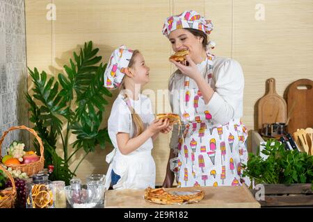 Dopo aver cucinato la pizza fatta a mano, è passato il tempo di consumo. La gioia dei momenti di mamma e figlia insieme dopo aver lavorato in cucina e gustando il gusto della pizza cotta al forno. Foto Stock