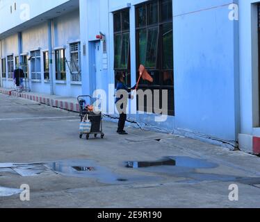 Bangkok, Thailandia - 2 febbraio 2021 : movimento offuscato di operaio femminile che indossa la maschera facciale usando il mop con il panno per pulire la finestra di vetro fuori di un edificio Foto Stock