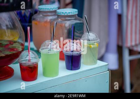 In un festival del cibo di strada, cocktail colorati sono esposti sul banco in bicchieri monouso con padelle, fumando dal ghiaccio artificiale all'interno. Vino Foto Stock