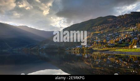Una vista panoramica sul lago di Voss Norvegia, l'acqua è ancora specchiata e il sole splende la sera, la casa sulla collina con bella Foto Stock
