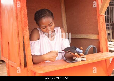 una donna africana che fa uso della sua macchina pos Foto Stock