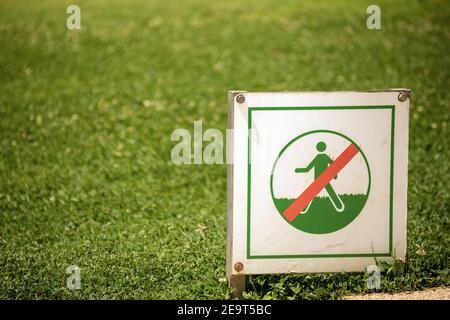 Primo piano di un segno di divieto di non camminare sull'erba con un prato verde soleggiato sullo sfondo. Barcellona, Spagna. Foto Stock