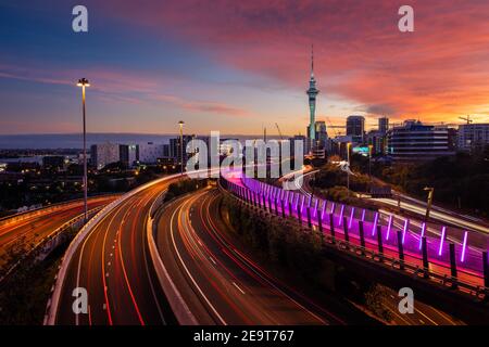 Vista dello skyline di Auckland, della Sky Tower e dell'autostrada con percorsi in auto all'alba. Foto Stock