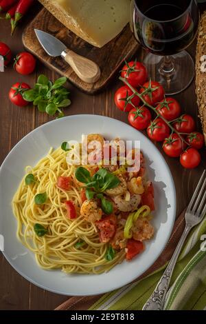 Spaghetti con gamberi, pomodori ciliegini e spezie su sfondo ligneo. Cibo sfondo. Vista dall'alto. Foto Stock