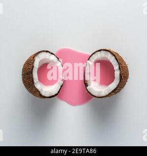Layout creativo fatto di cocco a metà con versamento di latte rosa. Concetto di cibo minimo. Foto Stock