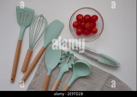 Set di utensili da cucina e pomodori ciliegini su sfondo bianco - direttamente sopra Foto Stock