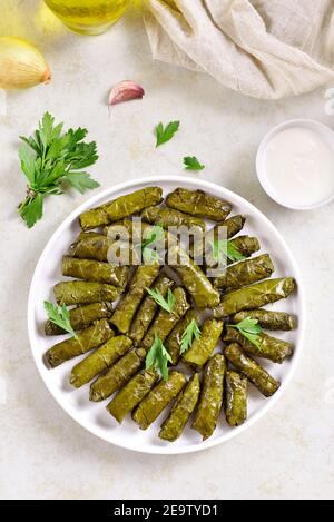 Dolma, foglie d'uva farcite con riso e carne su fondo di pietra chiaro. Vista dall'alto, disposizione piatta Foto Stock