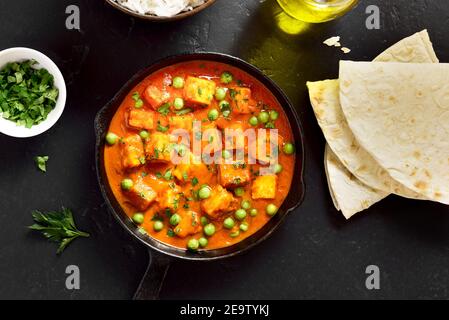 Paneer burro masala. Curry di formaggio cottage in stile indiano in padella su sfondo di pietra nera. Vista dall'alto, disposizione piatta Foto Stock