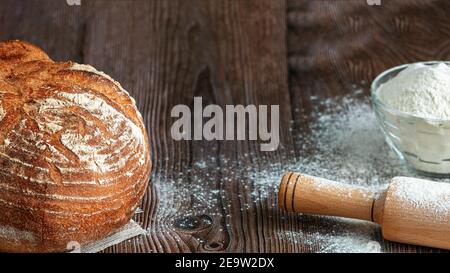 Primo piano di pane tradizionale di pasta acida su uno sfondo rustico di legno. Concetto di cottura tradizionale del pane lievitato. Cibo sano Foto Stock