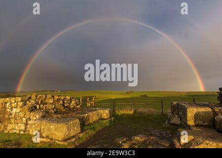 Un arcobaleno illumina il cielo oltre la porta nord di Milecasle 42 a Cawfield, il Muro di Adriano, Northumberland, Regno Unito Foto Stock