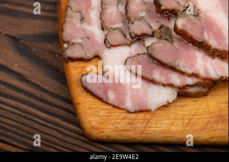 Bocchetto affumicato affettato su una tagliere di legno. Primo piano, messa a fuoco selettiva. Foto Stock