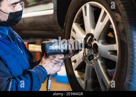 Meccanico che cambia la ruota dell'automobile in officina di riparazione auto Foto Stock