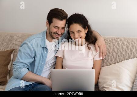 Una coppia millenaria che ama guardare insieme le foto di famiglia sul pc Foto Stock