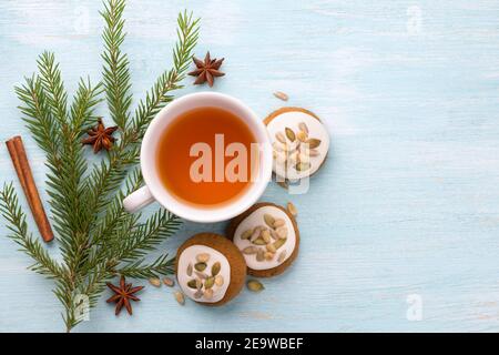 Una tazza di tè con fragrante miele pan di zenzero di Natale con smalto e noci, con rami di albero di Natale e spezie su uno sfondo azzurro, libero Foto Stock