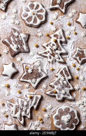 Biscotti al cioccolato fatti in casa di Natale decorati con glassa e zucchero in polvere su sfondo di legno, vista dall'alto Foto Stock