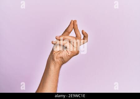 Braccio e mano di giovane caucasico su sfondo rosa isolato dita di scatto per il successo, facile e clic simbolo gesto con la mano Foto Stock