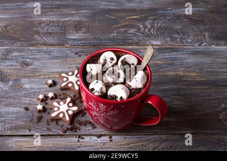 Cioccolata calda con marshmallows e cioccolato grattugiato in una tazza rossa su un tavolo di legno, stile rustico. Deliziosa bevanda di natale Foto Stock