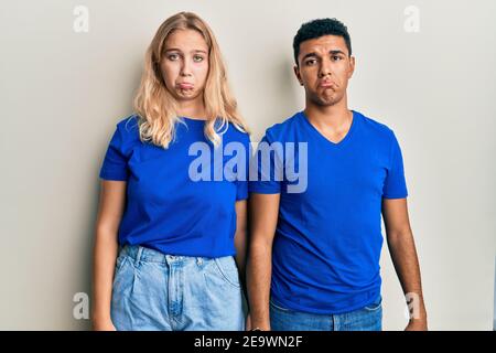 Giovane coppia interracial indossare abiti casual depresso e la preoccupazione per la sofferenza, piangendo arrabbiato e paura. Espressione triste. Foto Stock