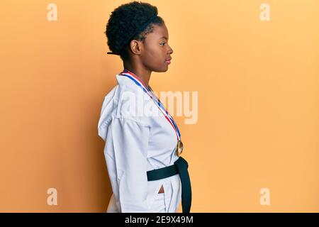 Giovane afroamericana che indossa kimono karate e cintura nera guardando a lato, rilassare profilo posa con viso naturale con sorriso fiducioso. Foto Stock