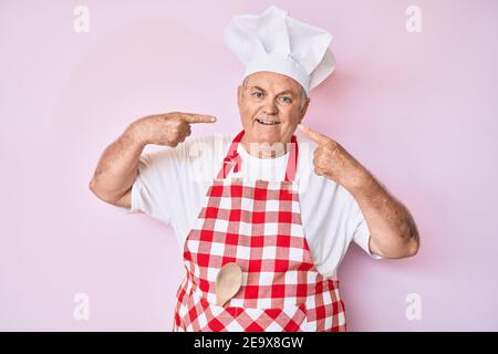 Capelli bianchi uomo vecchio è la cottura di insalata di verdure al tavolo.  guardare fotocamera Foto stock - Alamy