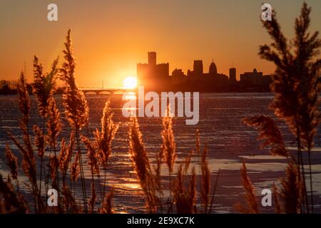 Detroit, Michigan - il fiume Detroit è pieno di ghiaccio invernale mentre il sole tramonta dietro lo skyline del centro. Foto Stock