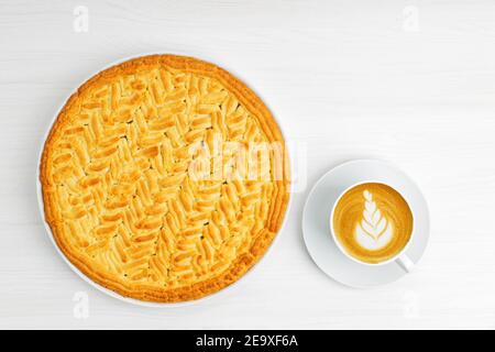 Torta al limone con uva spina fatta in casa e una tazza di cappuccino al caffè su un tavolo di legno bianco. Vista dall'alto. Foto Stock