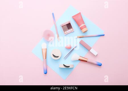 Strumenti e accessori per il trucco su sfondo blu e rosa. Concetto di bellezza. Composizione piatta, vista dall'alto Foto Stock