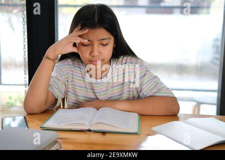 studentessa asiatica di ragazza che studia il sentimento duro stressato stanco esausto annoiato. educazione dei bambini Foto Stock