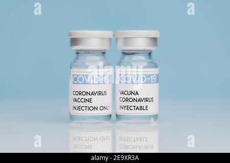 Fiale di vetro con vaccino COVID 19 poste sul tavolo su sfondo blu Foto Stock