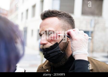 Primo piano di un artista di trucco irriconoscibile che mette il trucco su un volto dell'uomo hipster Foto Stock