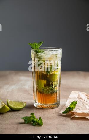 Rinfrescante mojito alcolico freddo con foglie di menta ghiacciata e tagliato lime su tavola di legno Foto Stock