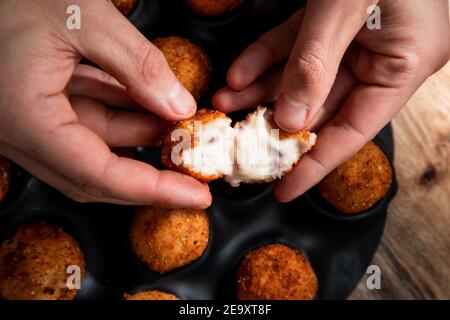 Dall'alto del raccolto anonimo chef che dimostra il ripieno di formaggio palla in crosta croccante in cucina Foto Stock
