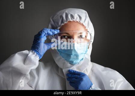 Dottore in dispositivi di protezione individuale (DPI), donna che indossa occhiali medici e maschera facciale, ritratto di infermiere in tuta professionale a causa del COVID-19 cor Foto Stock