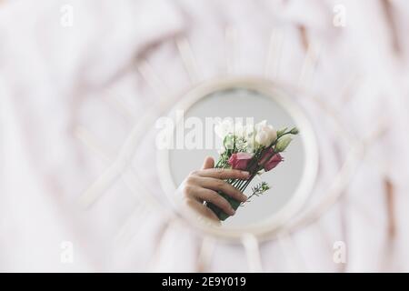 Fiori che tengono la mano riflessi nello specchio sullo sfondo di tessuto morbido. Ciao primavera e profumo floreale. Buon giorno delle donne e delle madri. Salute mentale con Foto Stock