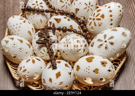 Happy Easter.White mano fatto uova di Pasqua con crocifisso in legno basket.Spring decorazione sfondo. Tradizione festiva per i paesi dell'Europa orientale Foto Stock