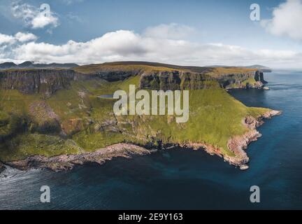 Vista aerea delle scogliere di Suduroy, la parte più meridionale delle Isole Faroe con cielo blu in un giorno di sole. Foto Stock