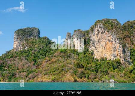 Una gigantesca formazione rocciosa si affaccia sulla sabbia bianca e sul mare blu di Railay Beach, a Krabi, Thailandia Foto Stock