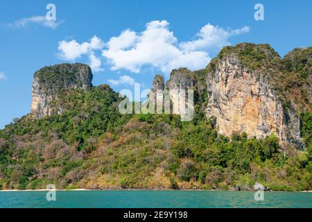 Una gigantesca formazione rocciosa si affaccia sulla sabbia bianca e sul mare blu di Railay Beach, a Krabi, Thailandia Foto Stock