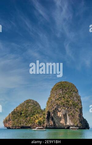 Una gigantesca formazione rocciosa sovraombra il mare blu di Railay Beach, a Krabi, Thailandia Foto Stock